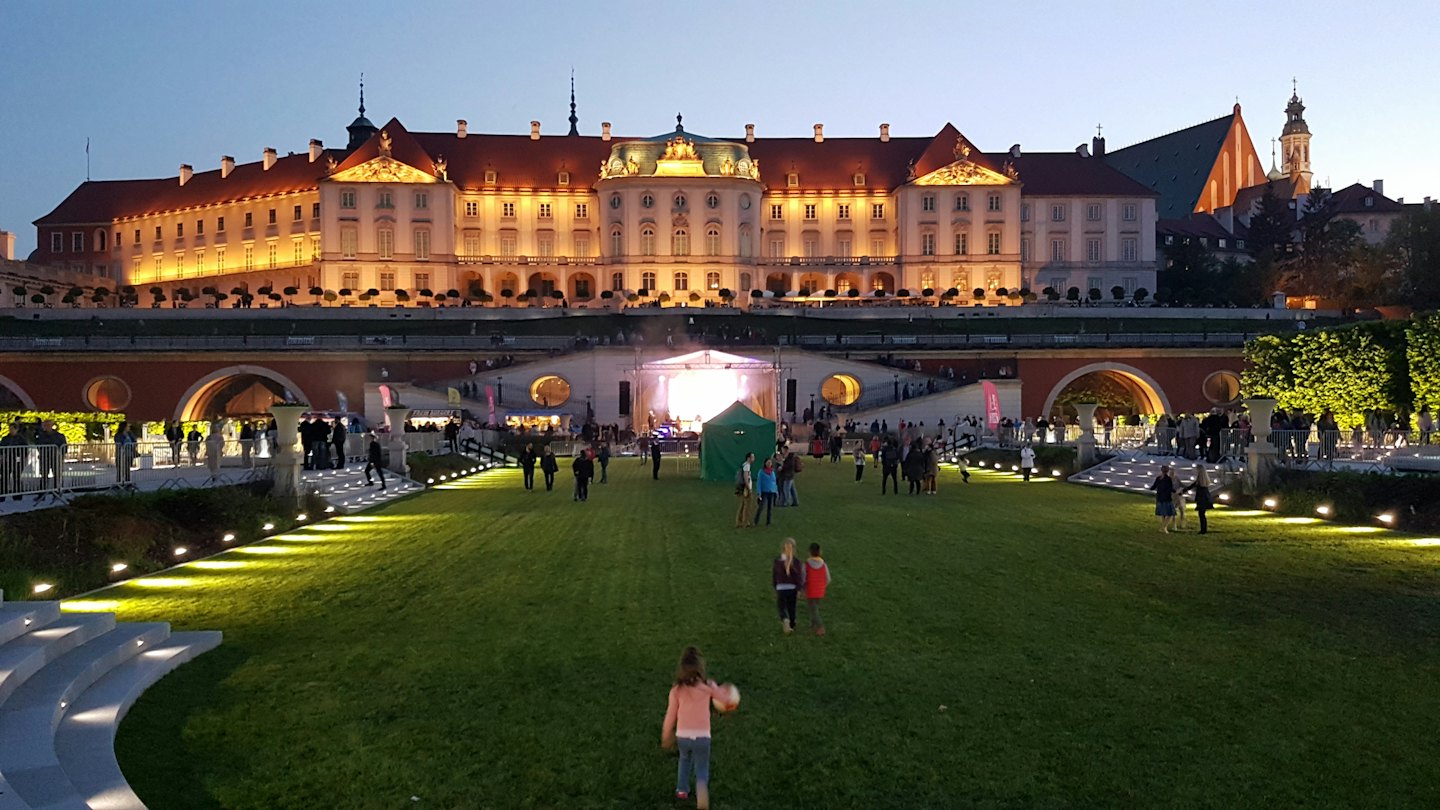 Mała dziewczynka bawi się na trawie podczas wieczornego koncertu.