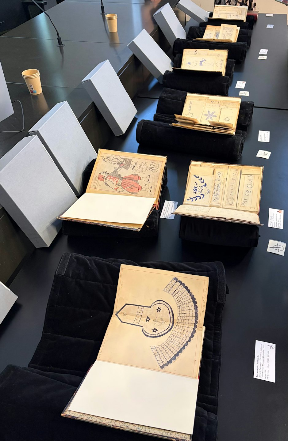 Historyczne rękopisy i dokumenty wyłożone na długim stole.